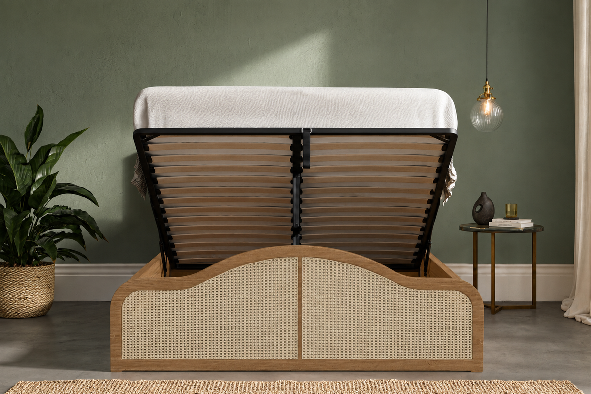 A wooden Ottoman bed frame with a raised platform and woven cane panels, shown open with a mattress partially folded back in a styled bedroom setting.